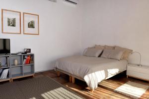 a white bedroom with a bed and a tv at Suite in Masseria in Plemmirio