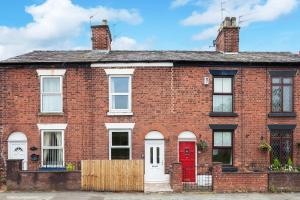 a red brick house with a red door at Cloud View Cottage in Congleton