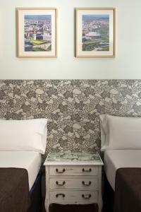 a hotel room with two beds and a nightstand between two beds at Pensión Laurel in Logroño