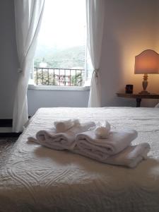 ein Bett mit weißen Handtüchern darauf und einem Fenster in der Unterkunft DORA AUREA in Levanto