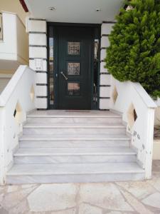 a black door on a white house with stairs at NEW PANORAMA STUDIOS ELECTRIC car ΦΟΡΤΙΣΗΣ ΣΤΑΤΙΟΝ in Paralion astros