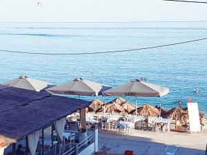 a beach with tables and umbrellas on the water at Sea La Vie - Studios Maria in Limenaria