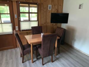 a dining room with a wooden table and chairs at Ferienhaus am Wäldchen in Uelsen