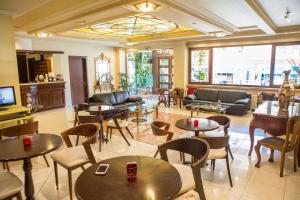 sala de estar con mesas, sillas y TV en Hotel Pella en Giannitsa