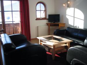 Sala de estar con 2 sofás negros y mesa de centro en Appartement Mayr, en Kirchdorf in Tirol