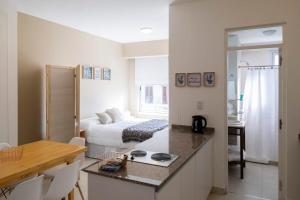 DEL SOL Apartamentos Salta في سالتا: مطبخ وغرفة نوم مع سرير في غرفة
