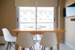 a dining room table with white chairs and a large window at DEL SOL Apartamentos Salta in Salta