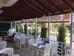 a patio with white tables and white chairs at Sun Apart Motel in Gumuldur