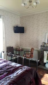 a bedroom with a bed and a tv on the wall at La Maison du Notaire - Chambre d'Hôtes - Huisdieren welkom in Melay