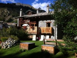 a house with a deck and a bench in the yard at Les Trompeurs chez Odette in Cogne