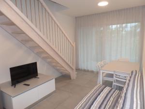 a living room with a tv and a table with chairs at Residence Melograno in Bibione