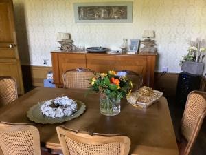 a dining room table with a vase of flowers on it at La Maison du Notaire - Chambre d'Hôtes - Huisdieren welkom in Melay