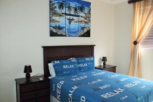 a bedroom with a bed with a blue comforter and palm trees at Uvongo Lucian Blue Flag Beach Apartment in Margate