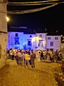 un grupo de personas de pie delante de un edificio por la noche en Casa da Rua Nova, en Castelo de Vide