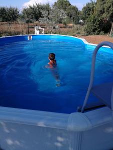 フォッローニカにあるAgriturismo Sant'Orsolaの青いスイミングプールでの子供の水泳