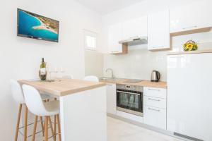 cocina con armarios blancos y encimera de madera en Apartment Holiday, en Makarska