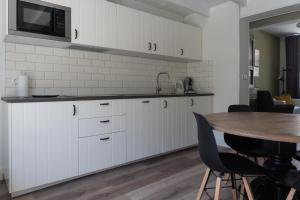 Una cocina con gabinetes blancos y una mesa de madera. en Het Dokhuis, en Middelburg 5 fotos más