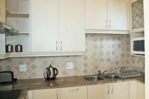 a kitchen with white cabinets and a sink at Uvongo Lucian Blue Flag Beach Apartment in Margate