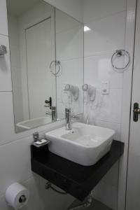 Baño blanco con lavabo y espejo en Klein Ville Dois Irmãos, en Dois Irmãos