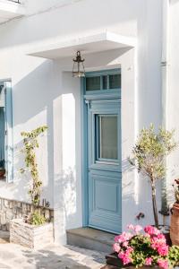 a blue door on a white house with flowers at Achinos guest house, Skopelos in Skopelos Town