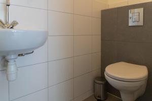 Un baño con un inodoro blanco y un lavabo. en Het Dokhuis, en Middelburg