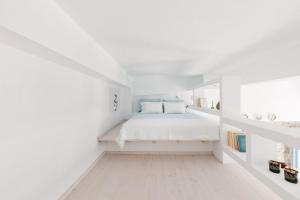 a white bedroom with a white bed and a window at Achinos guest house, Skopelos in Skopelos Town