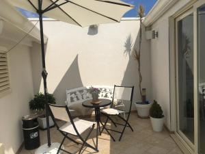 un patio con mesa, sillas y sombrilla en Marinella di Montalbano, en Punta Secca