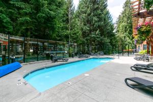 a large swimming pool with chairs around it at Beautiful Whistler Village Alpenglow suite queen size bed air conditioning cable and smartTV WIFI fireplace pool hot tub sauna gym balcony mountain views in Whistler