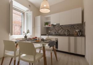 a kitchen with white cabinets and a table and chairs at Casa del Teatro in Città della Pieve