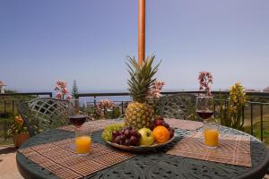 a table with a bowl of fruit and two glasses of wine at Paradise House Calheta in Calheta