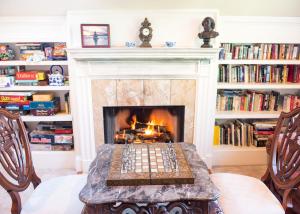 a fireplace in a living room with a table and chairs at Chiltern Inn in Bar Harbor