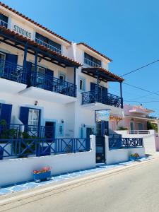 - un bâtiment blanc avec des balcons bleus dans une rue dans l'établissement Angistri's panorama apartments, à Skala