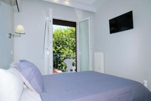 a white bedroom with a bed and a balcony at Limnia Gi in Myrina