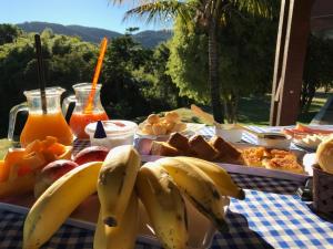 a table with bananas and bread and orange juice at Pousada Som das Águas Bueno Brandão in Bueno Brandão