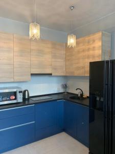 a kitchen with blue cabinets and a black refrigerator at Французский Бульвар ЖК Париж in Odesa