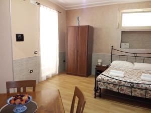 Un dormitorio con una cama y una mesa con un bol de fruta en B&B Al Centro Storico, en Agrigento