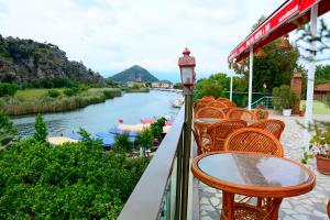 a balcony with tables and chairs and a river at Cinar Sahil Pansiyon in Dalyan