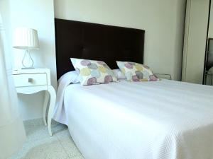 Una cama blanca con dos almohadas encima. en By The Beach, en Málaga
