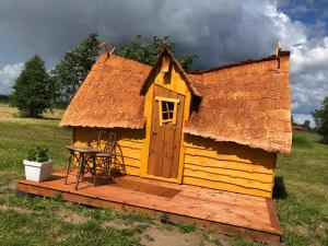 a small yellow house with a table on a deck at külalistemaja Kadrina mõisa kämpingud in Kadrina +8 photos