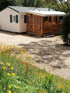 a cabin with a porch and flowers in front of it at MOBILHOME 3 CHAMBRES in Veyrignac