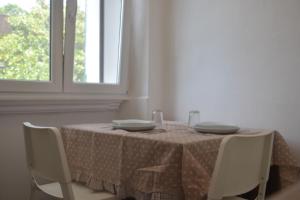 mesa de comedor con sillas blancas y ventana en Easy House, en Cormòns
