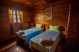 a bedroom with two beds in a wooden cabin at Roça Saudade Guest House in Trindade