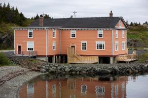 an orange house on the shore of a body of water at Hodge Premises in Twillingate