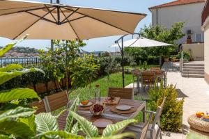 a table with an umbrella in a garden at Apartments Flora Trogir in Trogir