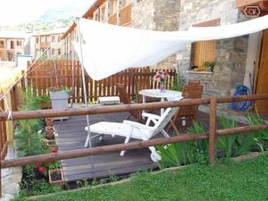 a wooden deck with a white umbrella and chairs at Unifamiliar con jardin VU-HUESCA-22-315 in Villanúa