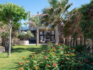 a garden with palm trees and flowers in front of a building at Evdokia Beach Resort in Gázion