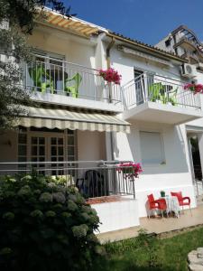 布德瓦Guest House Vila Bak的白色的房子,配有红色椅子和阳台