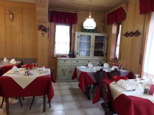a dining room with two tables with red tablecloths at Locanda Da Pierina in Santo Stefano di Cadore