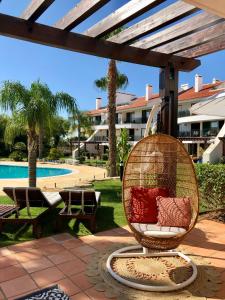 una silla de ratán sentada en un patio cerca de una piscina en Luxury T2 in Vila Sol Village en Vilamoura