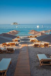 uma praia com cadeiras e guarda-sóis e o oceano em Hotel Riva by Aycon em Petrovac na Moru